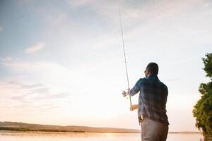 Jeune homme pêche à brumeux lever du soleil. photo