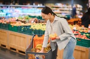 Jeune adulte femme choisir pommes dans épicerie magasin. mode de vie photo