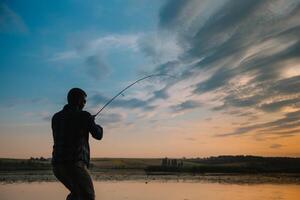 pêche. filage à le coucher du soleil. silhouette de une pêcheur. photo