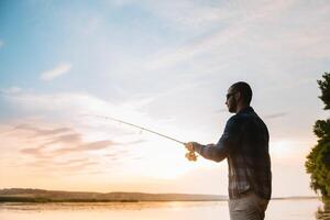 Jeune homme pêche à brumeux lever du soleil. photo