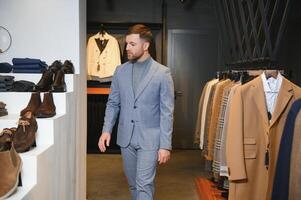 vente, achats, mode, style et gens concept - élégant Jeune homme dans costume dans centre commercial ou Vêtements boutique photo