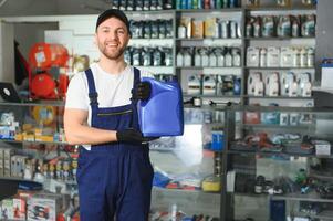 vendeur homme avec boîte de moteur pétrole dans auto boutique photo