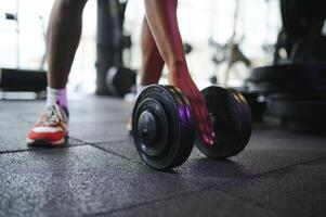 fermer de une homme prend une haltère dans le Gym photo