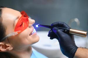 dentiste guérir le les patients les dents avec ultra-violet lampe dans le sien Bureau photo