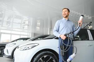 Jeune homme, vente électrique voitures dans le salle d'exposition. concept de achat respectueux de la nature voiture pour famille photo