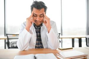 stressé Jeune Masculin Indien médecin dans blanc uniforme photo