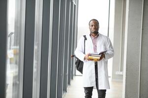 noir Masculin médecin étudiant portant une laboratoire manteau avec livre photo