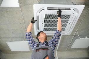 concentré Jeune Indien ingénieur réglage en haut air Conditionneur. photo