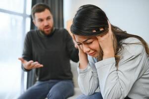 émotif homme faire des gestes et en criant à le sien épouse, Jeune couple ayant querelle à maison. national abuser de concept photo