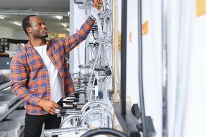 une grand sélection de l'eau robinets. africain américain homme choisit une des produits dans une sanitaire vaisselle boutique photo