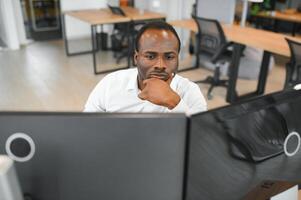 Afro-américain courtier travaux dans Bureau en utilisant poste de travail et une analyse La technologie photo