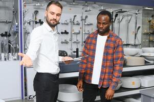 Jeune africain homme choisir robinets permanent avec vendeur près le vitrine de plomberie magasin photo