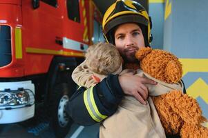 sapeur pompier en portant enfant garçon à enregistrer lui dans Feu et fumée, pompiers porter secours le garçons de Feu photo