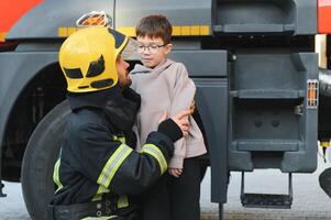 sapeur pompier en portant enfant garçon à enregistrer lui dans Feu et fumée, pompiers porter secours le garçons de Feu photo