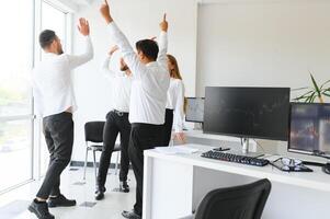 content hommes d'affaires en riant tandis que collaborer sur une Nouveau projet dans un bureau. groupe de diverse hommes d'affaires travail ensemble dans une moderne espace de travail photo