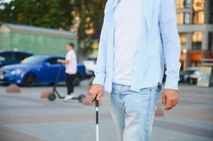 aveugle homme en marchant sur trottoir en portant bâton. photo