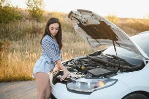 magnifique svelte fille dans chemise et short regards dans ouvert voiture capuche sur une route photo