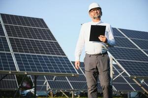 solaire Puissance plante. homme permanent près solaire panneaux. renouvelable énergie photo