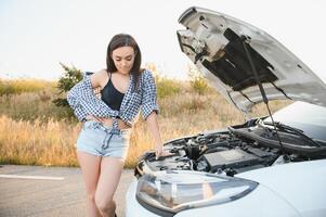 magnifique svelte fille dans chemise et short regards dans ouvert voiture capuche sur une route photo