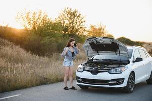 magnifique sexy femme près une cassé auto. confus femme Est-ce que ne pas connaître quoi à faire photo