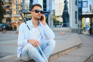 Jeune aveugle homme avec téléphone intelligent dans ville, appel photo