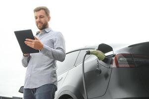 une homme des charges un électrique voiture photo