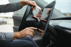 inconnue Jeune homme main lequel dactylographie nécessaire coordonnées sur navigateur écran tactile à l'intérieur le sien moderne voiture proche en haut photo