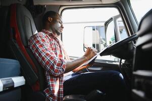 Jeune Beau africain américain homme travail dans remorquage un service et conduite le sien camion. photo