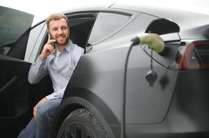 une homme des charges le sien moderne électrique auto. le concept de vert énergie photo