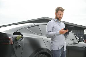 une homme des charges un électrique voiture photo