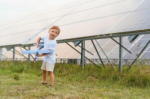 une peu garçon est ayant amusement près le solaire panneaux. le concept de solaire énergie. photo