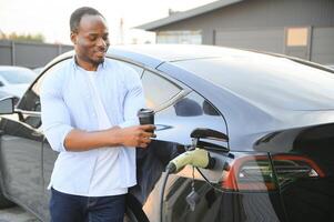 homme mise en charge le sien électrique voiture à charge station photo