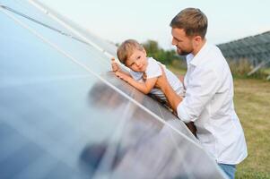 homme montrant peu enfant le solaire panneaux pendant ensoleillé journée. père en présentant à le sien enfant moderne énergie Ressource. peu pas à alternative énergie. photo