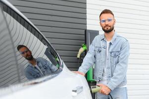 élégant homme inserts prise de courant dans le électrique voiture mise en charge prise photo