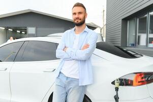 magnifique Jeune élégant homme est avec électrique voiture à jour mise en charge le véhicule photo