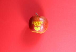 mûr Pomme avec mots je l'amour vous sur rouge Contexte. photo
