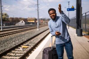 en colère homme avec une valise et mobile téléphone permanent sur une chemin de fer gare. photo