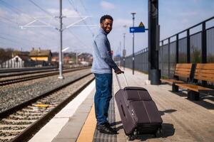 content homme avec valise permanent sur chemin de fer gare. photo