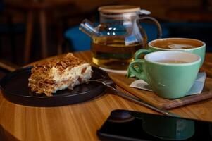 une tasse de café et une tasse de vert thé et gâteau sur une en bois table dans une café. photo