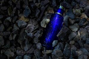 parfum foncé bleu transparent bouteille dans gravier ou corail Contexte photo