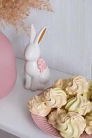 jaune-rose Meringue sur une rose assiette et une blanc porcelaine lapin avec une arc photo