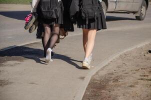 haute école élèves en marchant Accueil sur une agréable chaud printemps journée. haute qualité photo