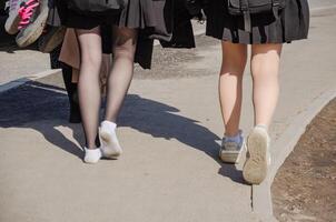 haute école élèves en marchant Accueil sur une agréable chaud printemps journée. haute qualité photo