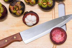 reine de fruit. mangoustans et couteau sur le en bois plaque. photo
