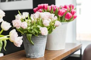 blanc et rose tulipes dans décoratif seaux sur le tableau. personne. photo