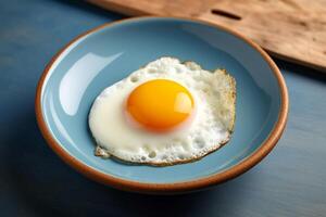 frit Oeuf sur céramique assiette sur bleu arrière-plan.. photo