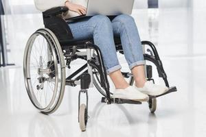femme handicapée de section basse assise en fauteuil roulant à l'aide d'une tablette numérique