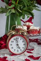 encore la vie dans Anglais style avec écarlate pivoines et rouge velours petits gâteaux avec sur une plateau, thé temps sur rouge antique l'horloge photo