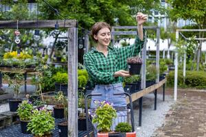 Jeune caucasien client est choisir exotique plante de le local jardin centre garderie avec achats Chariot plein de été plante pour fin de semaine jardinage et Extérieur photo