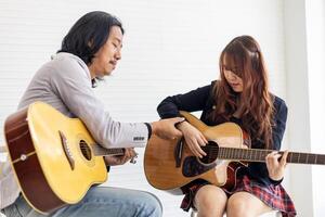 Jeune asiatique adolescent est apprentissage à jouer guitare par professionnel prof qui montrant Facile accords pour la musique classe école photo